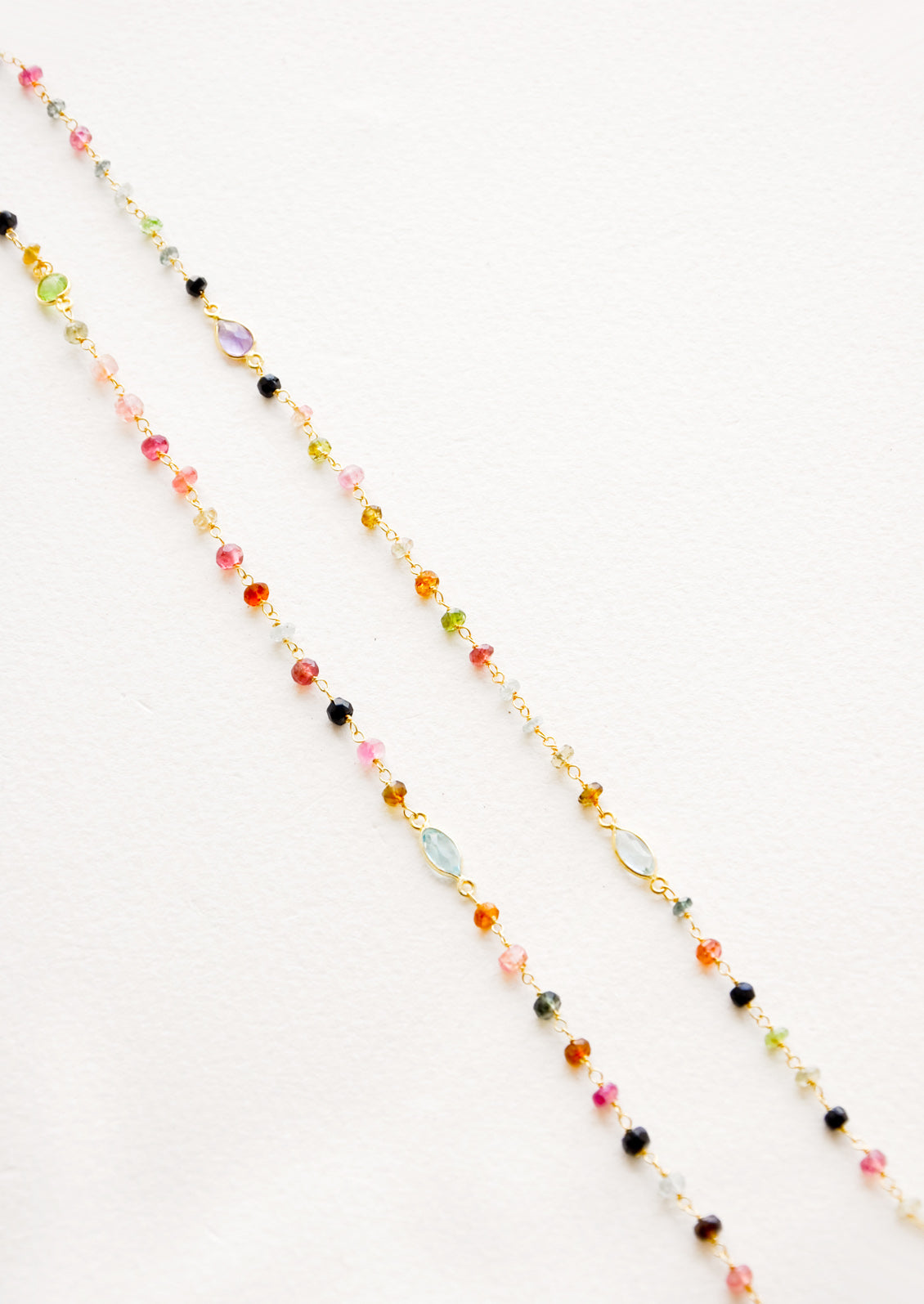 A long necklace with multicolor gemstones and tourmaline bezel.