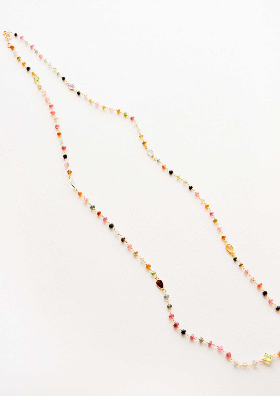 A long necklace with multicolor gemstones and tourmaline bezel.