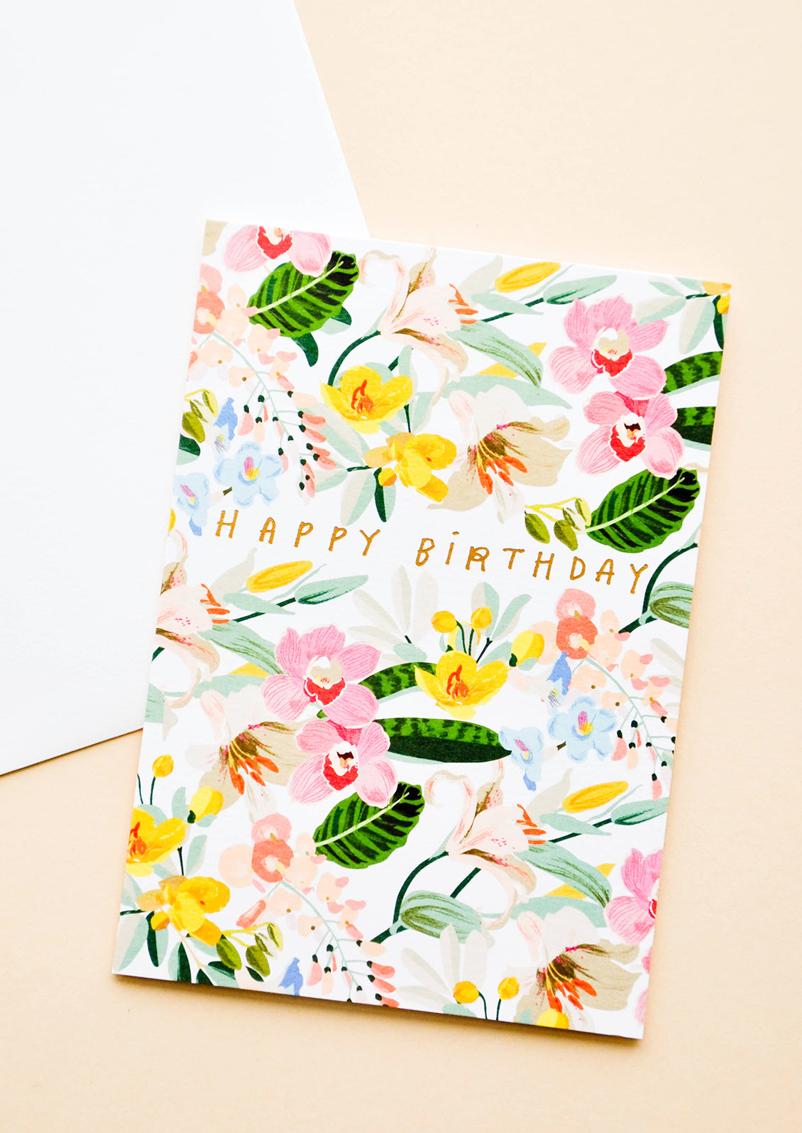 Greeting card with bright white floral background and gold lettering reading "Happy Birthday"