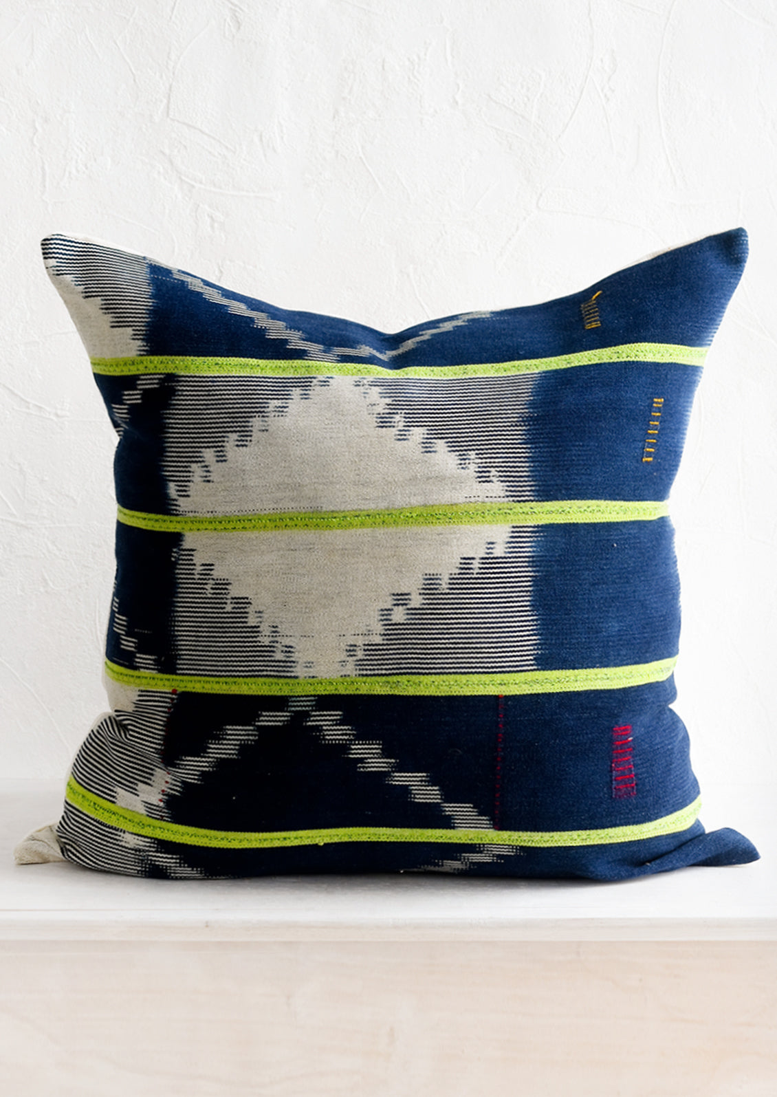 A vintage indigo baule fabric pillow in dark indigo with lime green stripes.