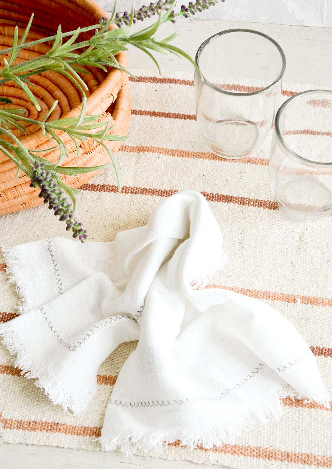 A serene table setting with light colored linens and clear glass cups