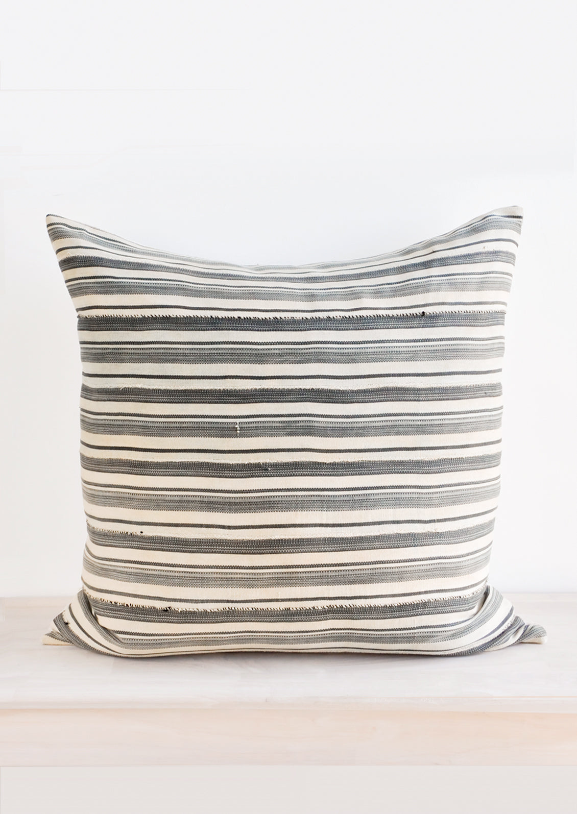 Square throw pillow in faded vintage fabric with allover tan and grey stripes