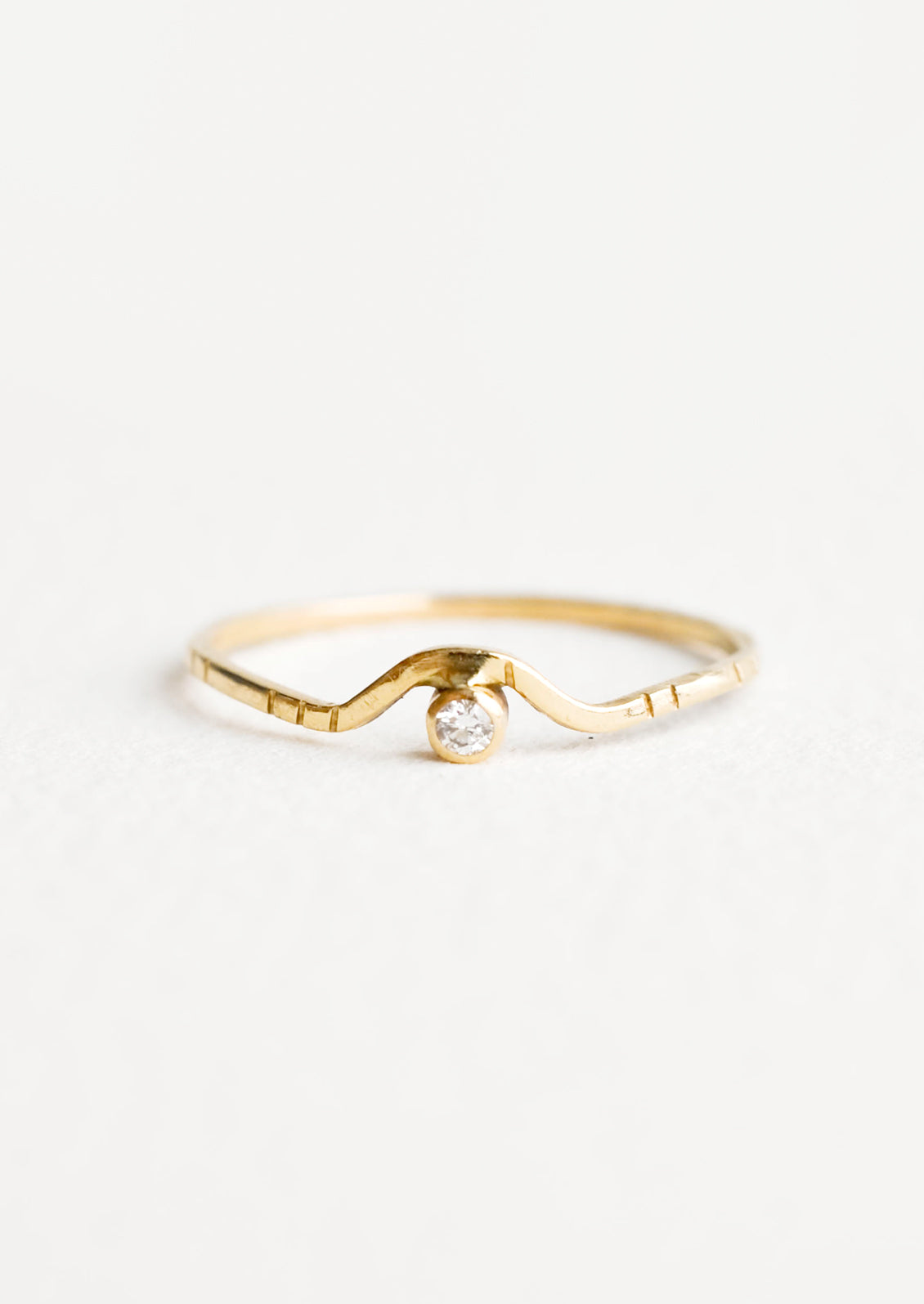 Yellow gold ring with etched decorative lines and a diamond set into an arched front.