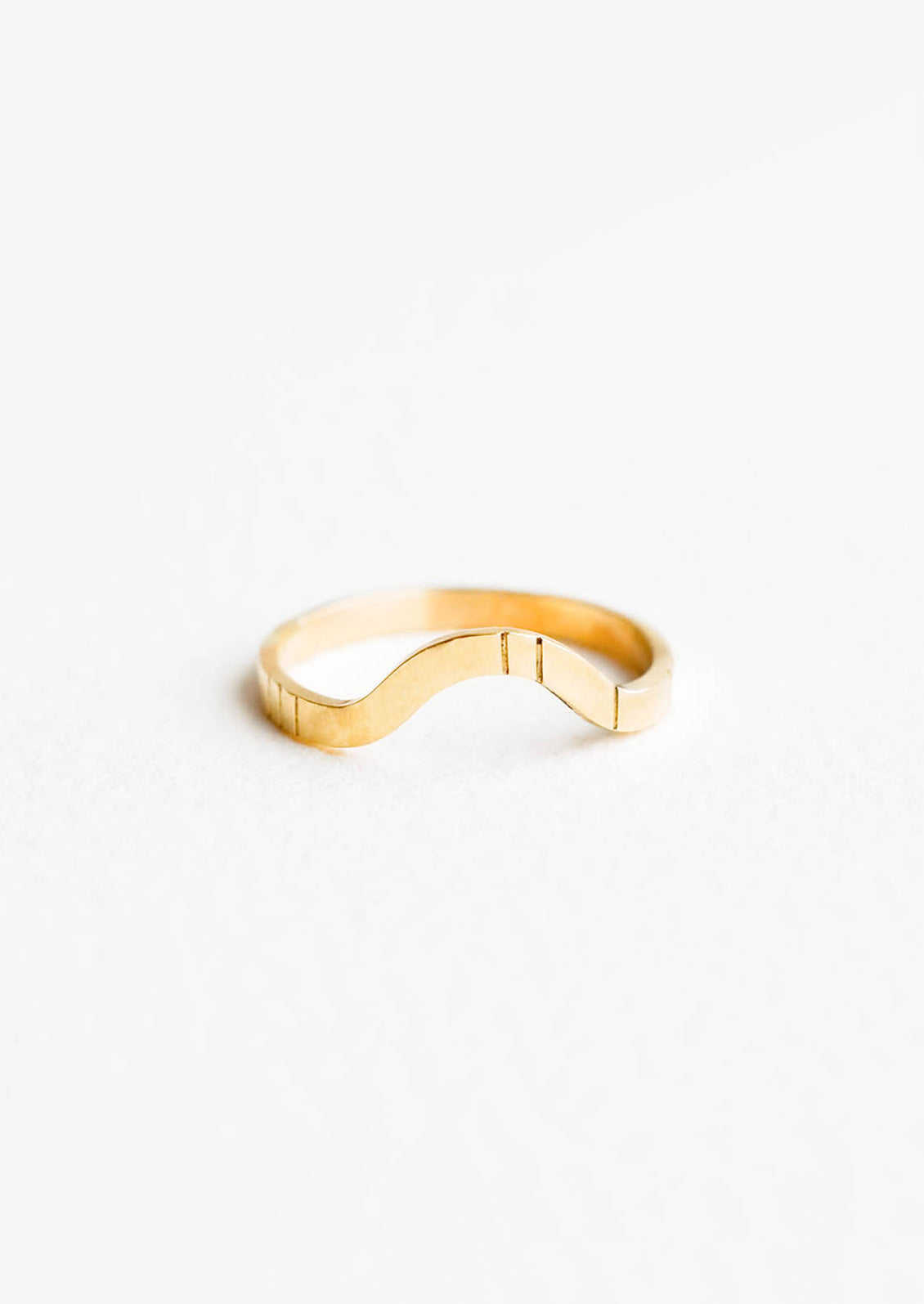 Yellow gold ring with medium size band, arced front, and etched decorative lines.